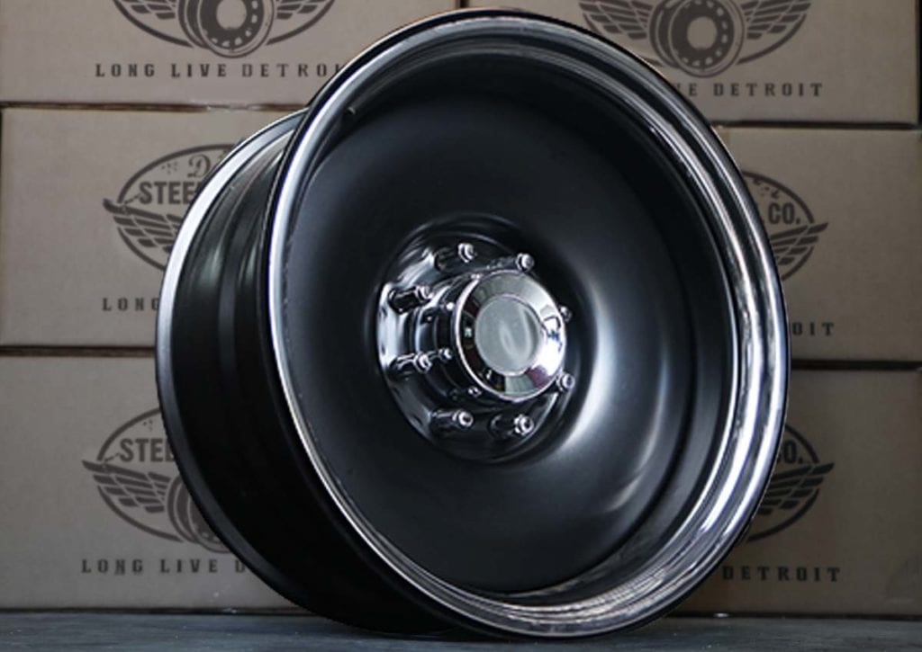 A black rim with silver rimmed rims sitting on top of a wall.
