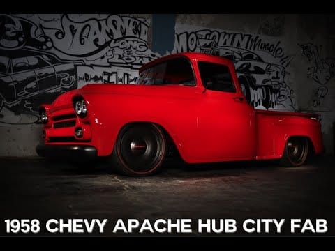 A red truck parked in front of a wall with graffiti.
