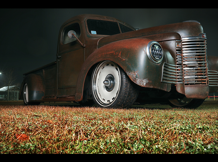 A rusted truck is parked in the grass.